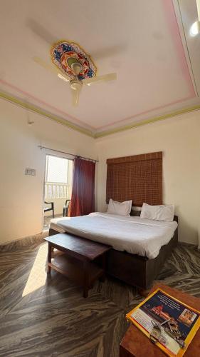 a bedroom with a large bed and a table at Mangalam Hotel and Restaurant in Lachhmangarh Sīkar