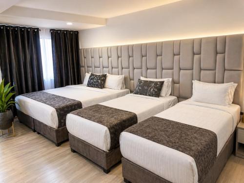 a hotel room with two beds and a large headboard at Aw Hotel Embassy Corner - Corferias, Embajada EEUU & Vive Claro in Bogotá
