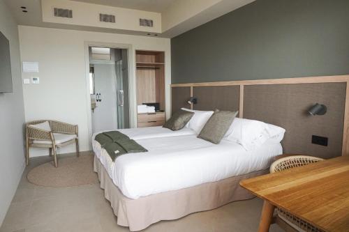 a bedroom with a large bed and a table at Hotel Restaurant Juanito Platja in Sant Carles de la Ràpita