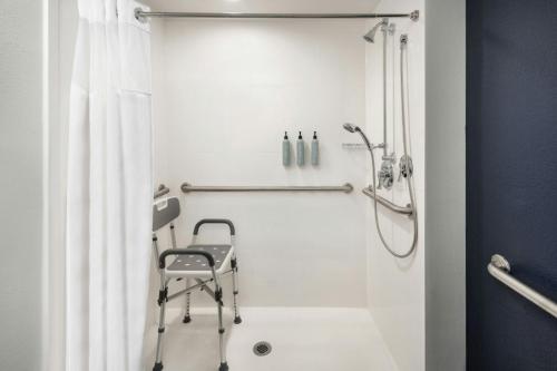 a bathroom with a shower with a chair in it at Courtyard by Marriott across Universal Orlando in Orlando