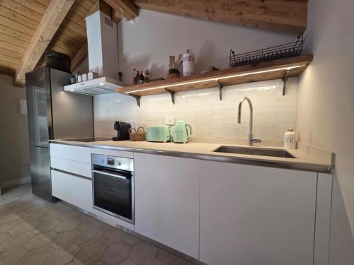 a kitchen with white cabinets and a sink at Lakeview Jonny house on the roofs in Lezzeno