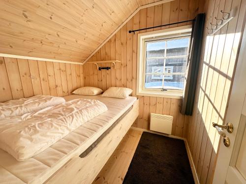 a bed in a wooden room with a window at Trysilbua 1173 in Trysil