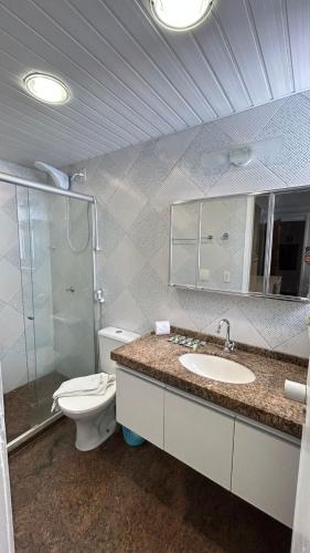 a bathroom with a toilet and a sink and a mirror at Flat Atlântico Neto in Fortaleza