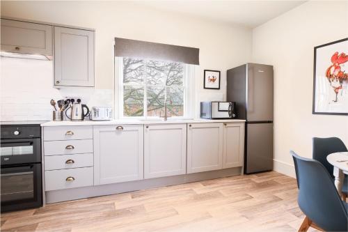 a kitchen with white cabinets and a refrigerator at Dairy Green Flat in Shifnal