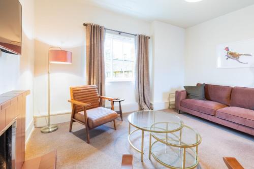 a living room with a purple couch and a glass table at Dairy Green Flat in Shifnal