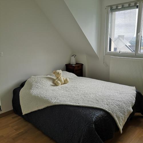 a teddy bear sitting on a bed in a bedroom at Ker valou in Hénansal