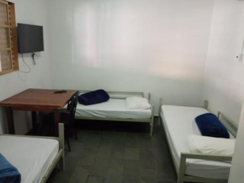 a room with three beds and a desk and a table at Hotel Kairós in Campinas