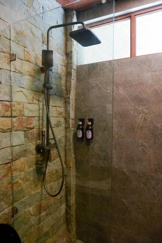 a shower in a bathroom with a stone wall at Layag La Union in san juan la union