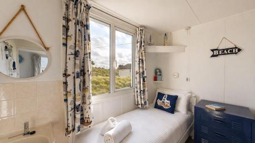 a small bedroom with a bed and a window at F71 Elova, Riviere Towans in Hayle