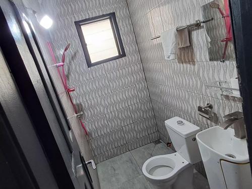 a bathroom with a toilet and a sink and a window at 2 CHAMBRES SALON MEUBLé in Yamoussoukro