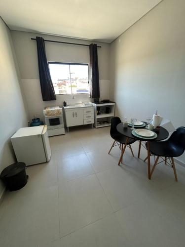 a living room with a table and chairs and a kitchen at 04 Studios centro,proximo a rodoviaria-itapeva sp in Itapeva