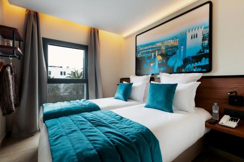two beds in a hotel room with a large window at MIA Urban Detroit Tanger in Tangier
