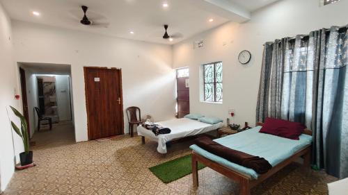 a room with two beds and a couch and a clock at Hotel Kalzug in Katihār