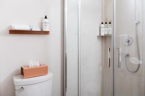 a bathroom with a shower and a toilet with a box on it at Maison Hôte in Magog-Orford