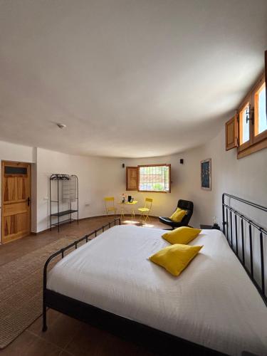 a bedroom with a large bed with yellow pillows at Cortijo de las Piedras in Lubrín