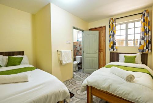 a bedroom with two beds and a bathroom at Miriam Inn, Chaka in Nyeri