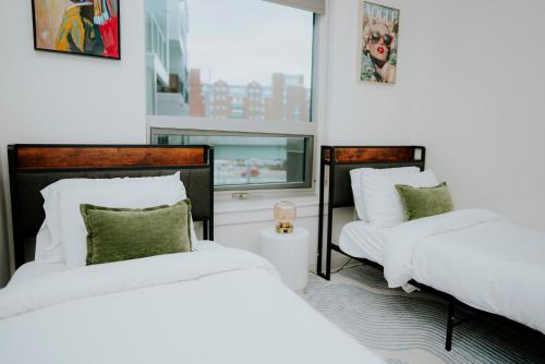 a bedroom with two beds and a flat screen tv at Luxury 2BR Apartment with Pool, Balcony & Parking in Cambridge