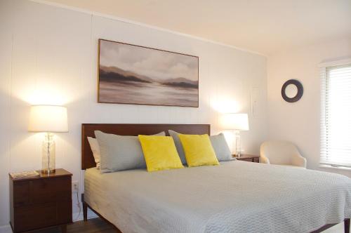 a white bedroom with a bed with yellow pillows at Bethany Ocean View Condo by the sea 1st of 2 in Ocean View