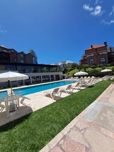 a swimming pool with lounge chairs and umbrellas at Carilo - semipiso 3 ambientes 1ºpiso in Carilo