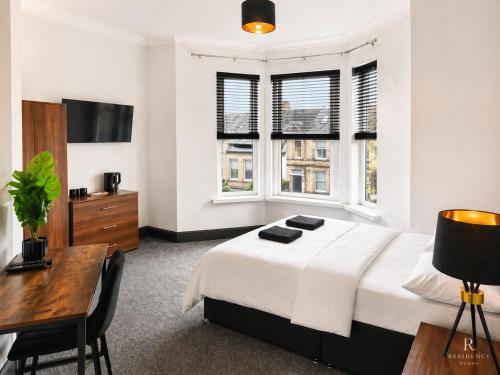 a bedroom with a bed and a desk and windows at Residency rooms Liverpool in Wallasey