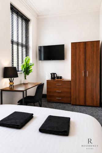a bedroom with a bed and a desk and a tv at Residency rooms Liverpool in Wallasey