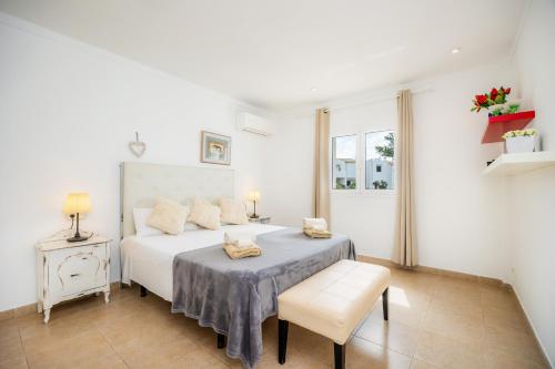 a white bedroom with a bed and a chair at Villa Sa Caleta de Cala D'or in Santanyi