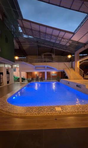 a large blue swimming pool in a building at Amazon Garden Suites - Recojo del aeropuerto incluido in Pucallpa