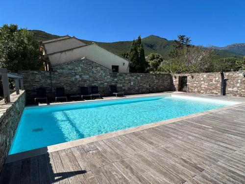 a swimming pool in front of a stone building at Appartement en résidence d'exception avec piscine dans le cap corse in Sisco