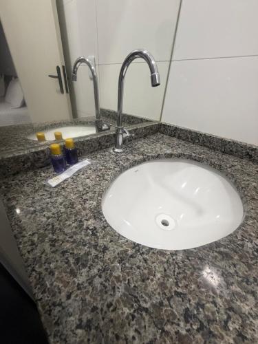 a bathroom counter with a sink with two faucets at Amazon Loft 09 in Sorriso