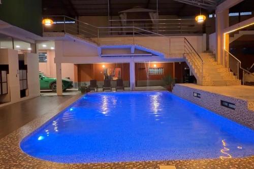 a large blue swimming pool in a building with stairs at Amazon Garden Suites - Recojo del aeropuerto incluido in Pucallpa