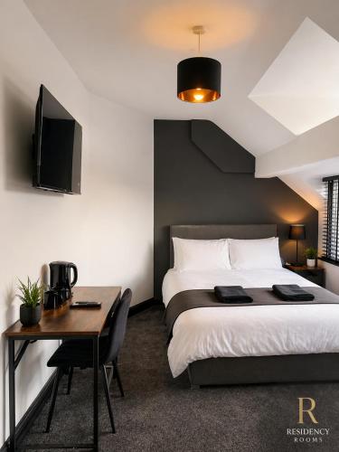 a bedroom with a bed and a desk and a tv at Residency rooms Liverpool in Wallasey