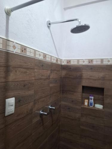 a bathroom with a shower with wooden walls at Hostal Las Armonías 3 in Panajachel