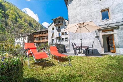 a group of chairs and an umbrella in a yard at Vallemaggia Green House in Sornico