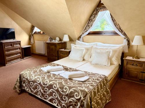 a bedroom with a bed with two towels on it at Hotel Dwór Karolówka in Zakopane