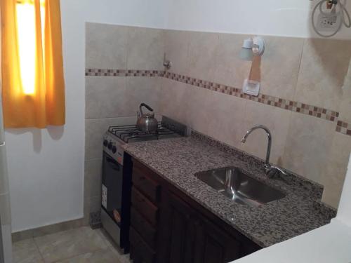 a kitchen with a sink and a stove at Departamentos Algarrobo in Arroyo de Los Patos