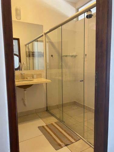 a glass shower in a bathroom with a sink at Recanto da Praia Pousada in São Miguel do Gostoso