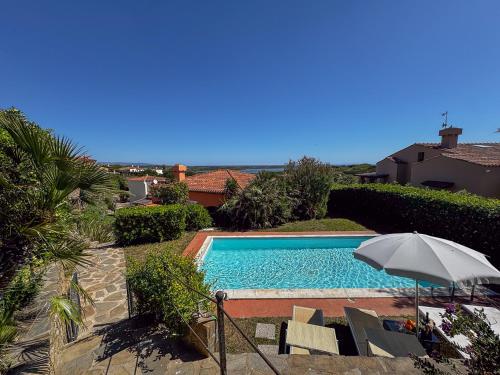 a swimming pool with an umbrella and some chairs at Villa Gilda - Private Pool by Host Hero in Stintino