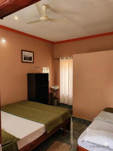 a bedroom with two beds and a ceiling fan at Belandoor Nature Nest in Sringeri