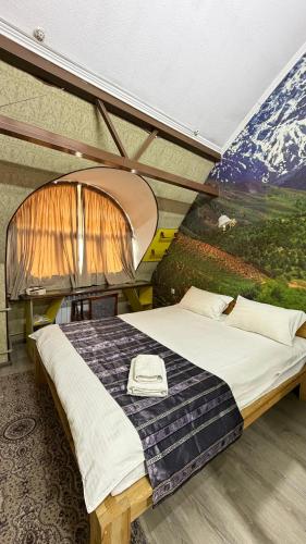 a bedroom with a large bed with a painting on the wall at Eco House in Osh