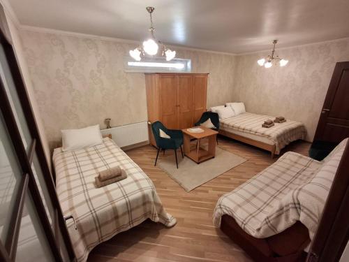 a room with two beds and a table and a chair at Apartmenti Ezerkrasti in Jaunpils