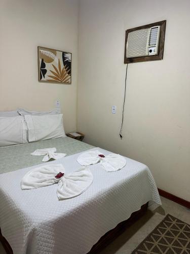 a bedroom with a bed with white sheets and a fan at Pousada Meraki Paraty Mirim in Paraty
