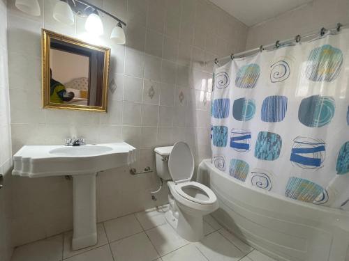 a bathroom with a sink and a toilet and a shower curtain at Bright Bay Garden Suite in Montego Bay