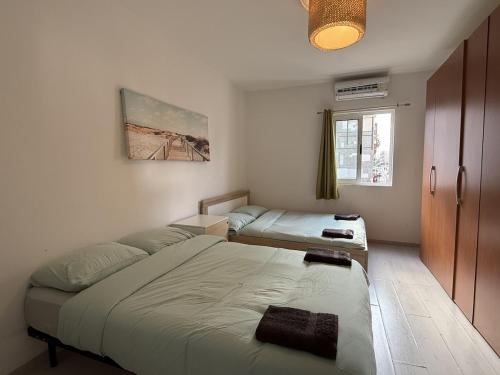 a bedroom with two beds and a window at Calypso 3 Large Stylish Apartment in Paceville with Mercury Tower View Ideal for Groups in St. Julianʼs