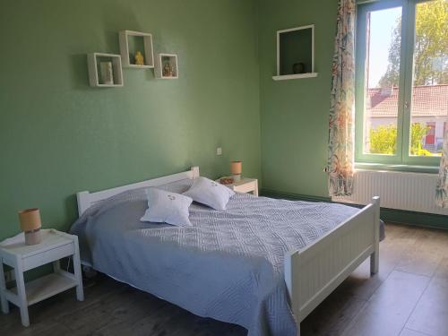 a bedroom with a bed with a blue comforter and a window at demeure à la campagne in Conchy-sur-Canche