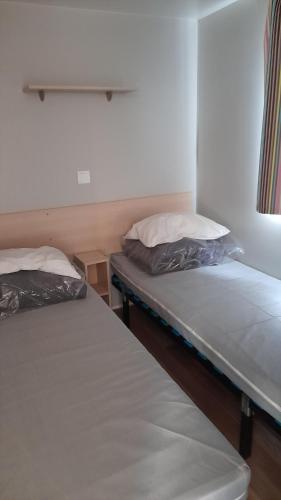 two twin beds in a room withthritisthritisthritisthritisthritisthritisthritisthritisthritis at Mobil Home AGDE Hérault in Agde