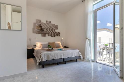 a white bedroom with a bed and a large window at NURAS - Casa Aurelia square view old town in Alghero