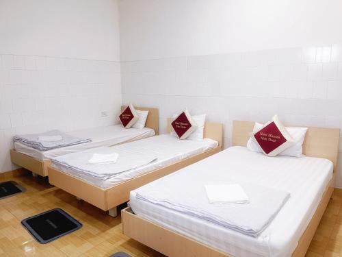 three beds in a room with white and red pillows at Mimosa 6 Hotel - Phan Rang in Phan Rang–Tháp Chàm