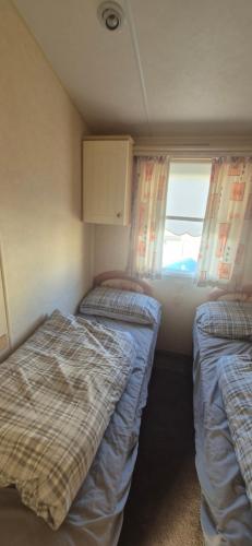 two beds in a small room with a window at The salsbury lyons robin hood park,rhyl in Meliden