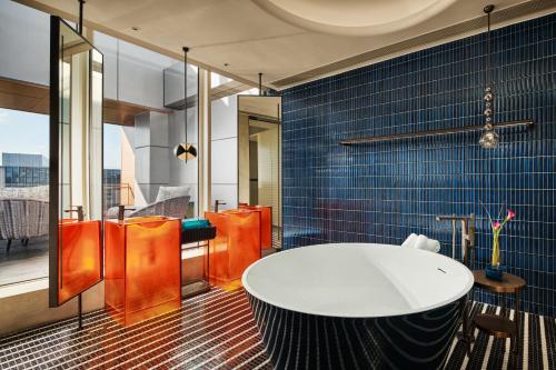 a bathroom with a white tub and blue tiles at Hotel Indigo Shanghai Harbour City by IHG in Zhenghai