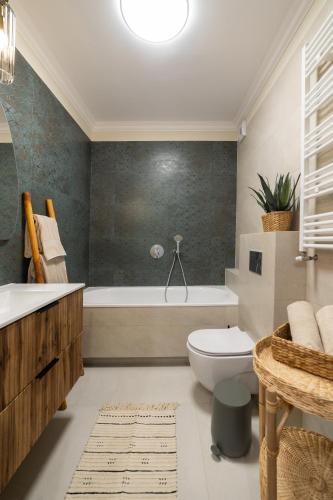 a bathroom with a tub and a toilet and a sink at Milla Apartamenty 102 in Zamość
